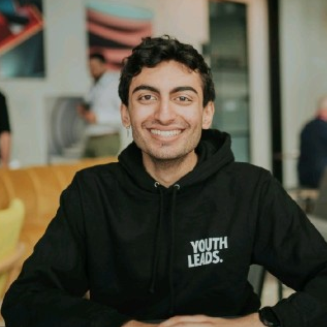 Young man smiling at the camera, indoors, wearing a black hoodie